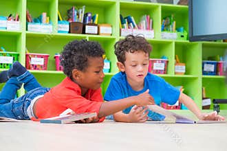 Two boy kid lay down on floor and reading tale book in preschoo