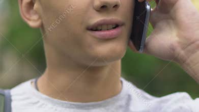Teenage boy answering phone call, arranging meeting with friends, close up