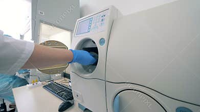 Laboratory worker loads the machine in a laboratory room.