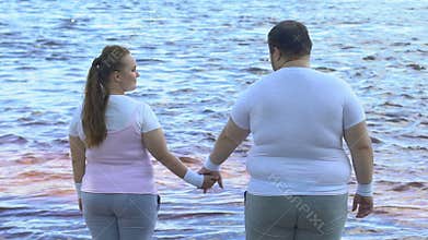 Obese man taking girlfriends hand, couple enjoying beautiful view of river