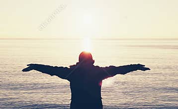 Praise rejoice person hope silhouette celebrating against sea ocean water arms up beating Coronavirus