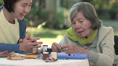 Elderly woman and daughter in the needle crafts occupational therapy for Alzheimerâ€™s or dementia