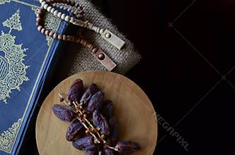holy quran with dates fruits and tasbih beads isolated at dakr background, suitable for ramadhan kareem