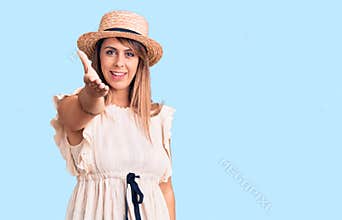Young beautiful woman wearing summer hat and t-shirt smiling friendly offering handshake as greeting and welcoming