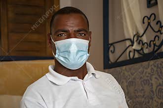 Portrait of a dark-skinned man about 40 years old in a medical mask in the room.Concept: test for coronavirus, tourist season duri