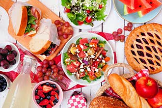 Summer picnic food table scene. Overhead view on a white wood background. Copy space.