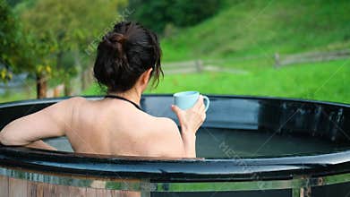 Young woman in an open-air bath with a view of the mountains.