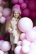 Happy smiling, laughing little girl in beret playing with pink, purple balloons, outdoors. childrens emotions.