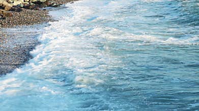 Beautiful sea waves on a pebble beach. Atlantic ocean beach sunsets. Water texture