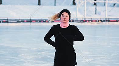 Young blonde woman figure skating on public ice rink