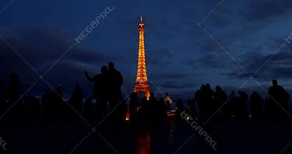 People and tourists walk on the Palais de Chaillot esplanade after sunset to photograph the Eifell tower