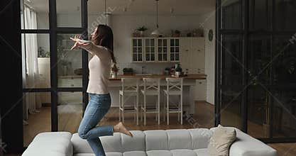 Carefree young active happy woman dance on sofa at home