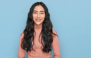 Hispanic teenager girl with dental braces wearing casual clothes with a happy and cool smile on face