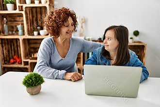 Mature mother and down syndrome daughter using computer laptop at home