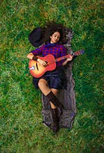 Beautiful brunette is playing the guitar and enjoying the simple life in the countryside