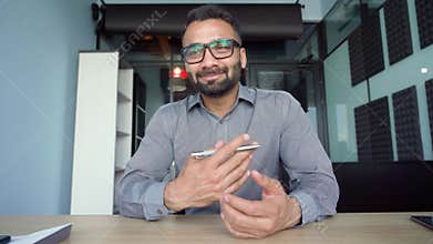 Webcam view of indian businessman talking to employees in office remotely.