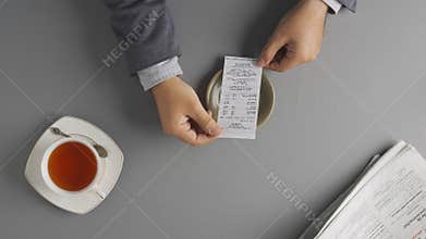 Male holding looking at bill at cafe or restaurant, checking the final payment sum before paying for service or product.