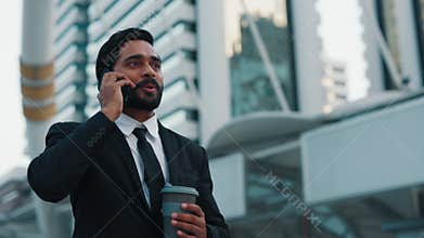 Happy businessman engrossed in telephone conversation walking outside