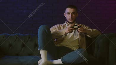 A young guy playing console. Male cybersport, play games online at home. He started a new game chapter now. Adult young