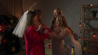 Group of young women friends celebrating bachelorette party at home, bridesmaids meeting the bride at party, smiling and