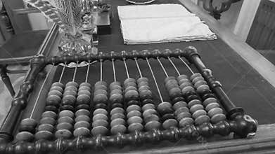 Old abacus, counting frame lies on the table in office. Black and white video