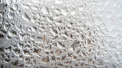 A close-up of double-glazed window condensation in winter, due to excessive moisture in the house, happens when the seal