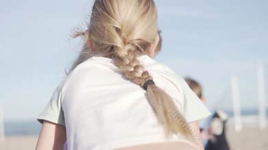 a girl with a thick long braid whispers in her friend's ear