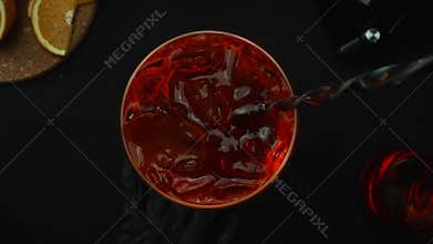 Macrography of mixing Negroni cocktail from a top-down perspective. Comestible.
