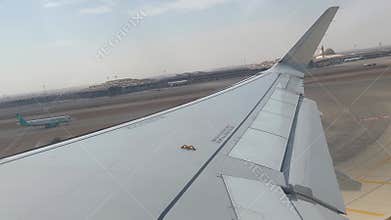 View from the cabin porthole of an airliner. A plane is driving fast on a runway