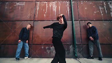 Cool b-boy performing somersaults on city street, team of break-dancers dancing outdoors, hobby time