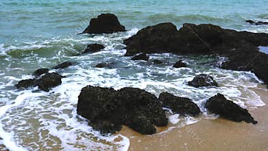 Sea waves crashed against the big rocks on the beach.