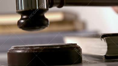 Gavel falling on sounding block beside books