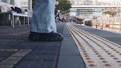 Train passengers approach the edge of the platform and wait for the train. Tactile paving. Assistance for the visually