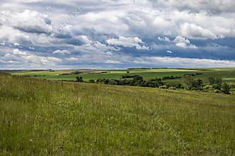 Vast green fields under dramatic clouds in the countryside