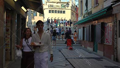 Venice Italy July 2025 tourists walking bridge lively street with restaurants