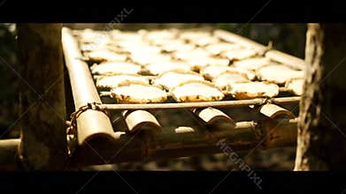 Slices of Cassava Drying on Bamboo Rack Under Sunlight in Rural Setting Preparation of Traditional Snacks and