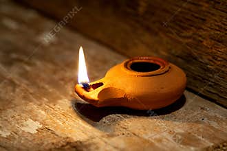 Ancient Middle Eastern oil lamp made in clay on wood table