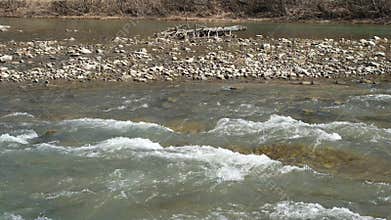 Mountain river carries and traps organic debris, such as driftwood.