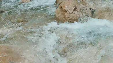 Dynamic close up view of fast moving turquoise stream with rapids and waterfalls