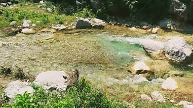 Crystal clear stream flowing through a rocky landscape with sunlit water rapids