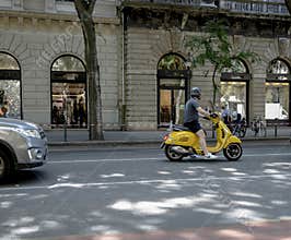 Man riding yellow scooter on city street