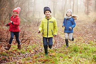 Three Children Running Through Winter Woodland