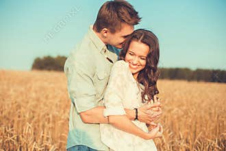 Young couple in love outdoor.Couple hugging.Young beautiful couple in love staying and kissing on the field on sunset.