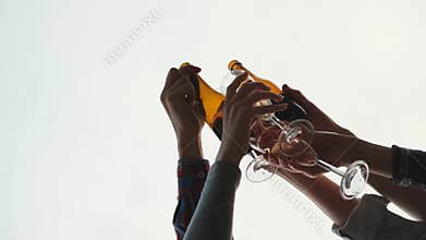 Friends party on beach at sunset. Women and men have fun, drink beer and wine, dance and laugh.