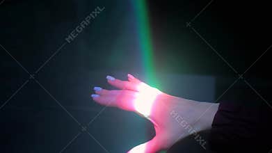 Woman moving hand under colorful laser rays - close up view - visuals concept