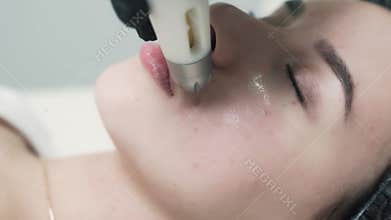 Close-up of cosmetologist hands doing hydro-peeling to a beautiful young client