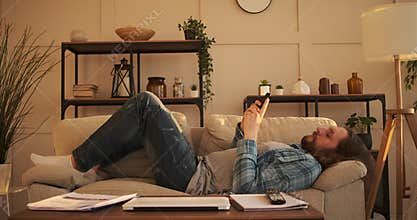 Frustrated man text messaging on mobile phone at home