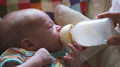 Mother feeding her newborn baby from bottle. Baby is drinking from his bottle