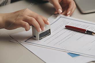 Close up on woman`s notary public hand stamping the document. Notary public concept