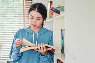 Beautiful young girl standing in the library at home with books, Woman reading a book